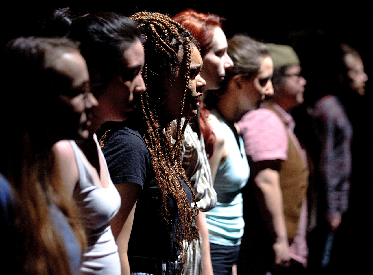 Various women in casual clothing stood in a line on stage.