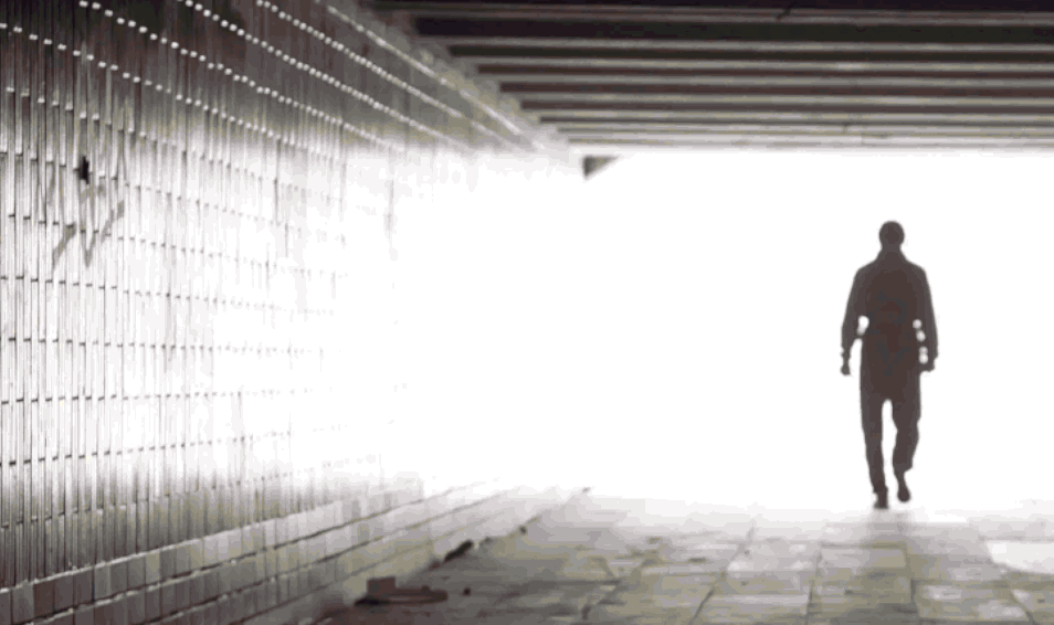 Silhouette of a person walking into a tiled tunnel