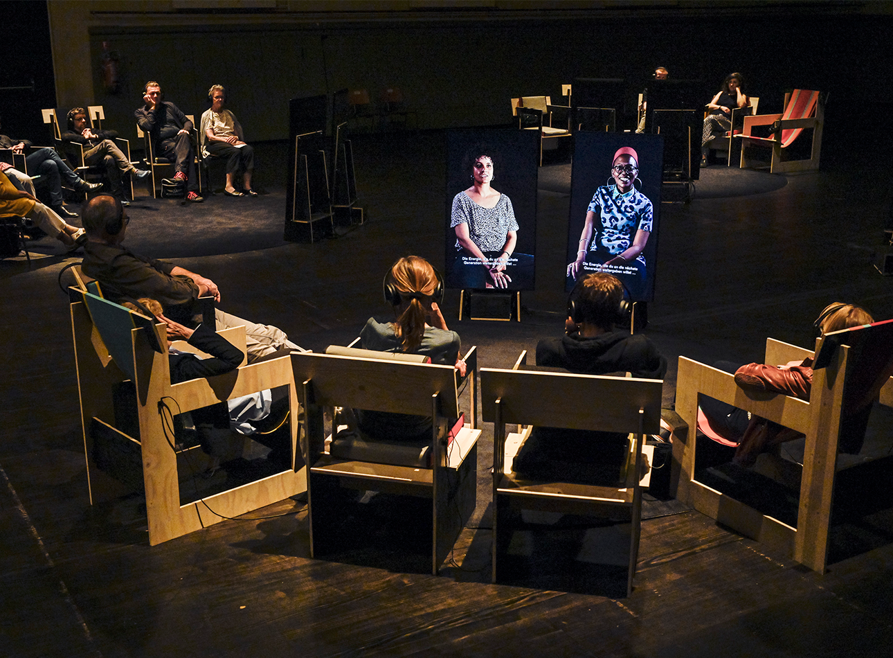 2 screens are set up in front of 4 chairs depicting 2 people. The same scene is replicated in the background.
