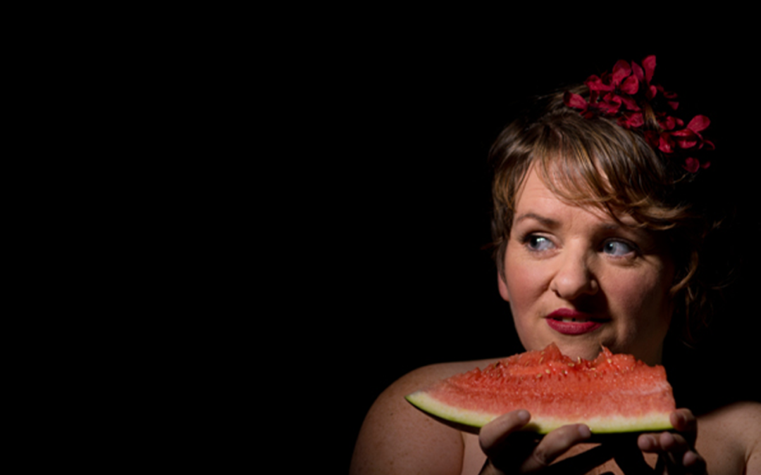 Woman holding a watermelon slice in front of a black background