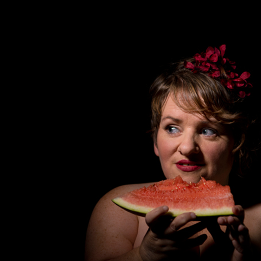 Woman holding a watermelon slice in front of a black background