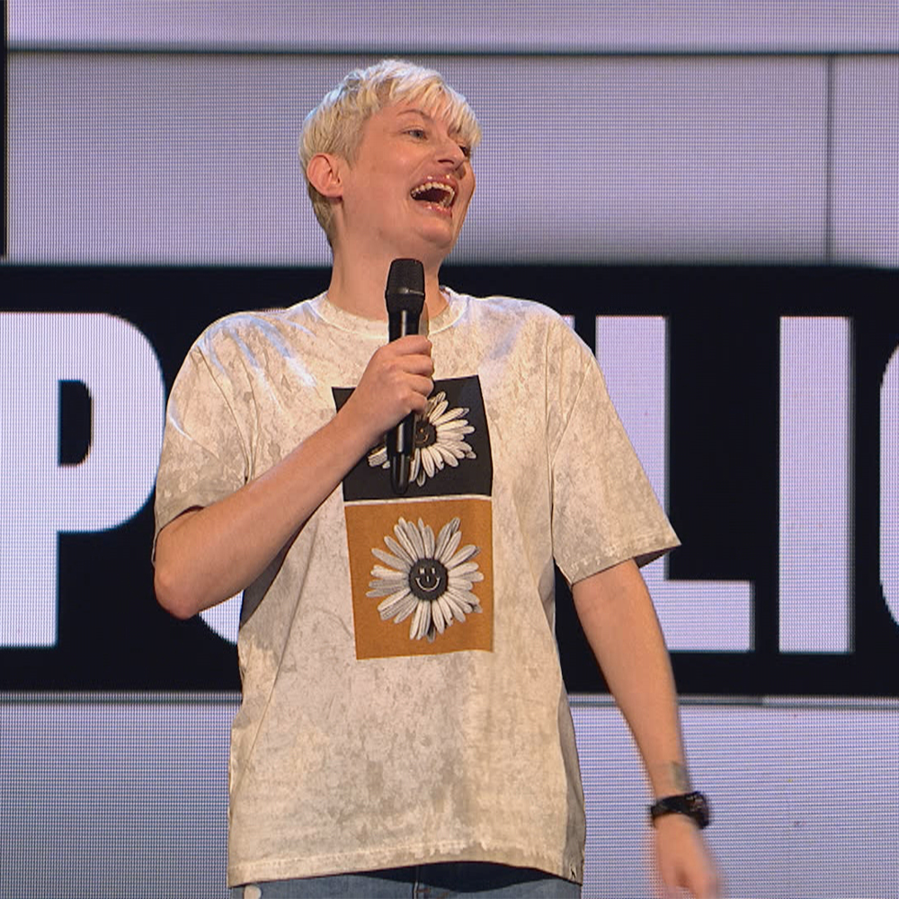 Harriet Dyer on stage in t shirt with microphone, laughing
